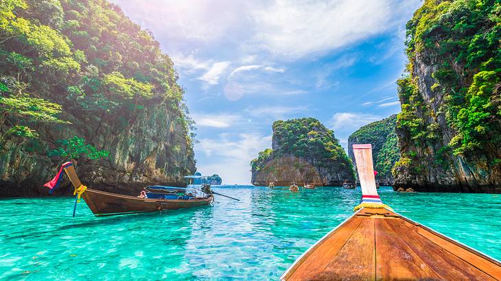 Two boats in the clear waters between greenery-covered limestone cliffs