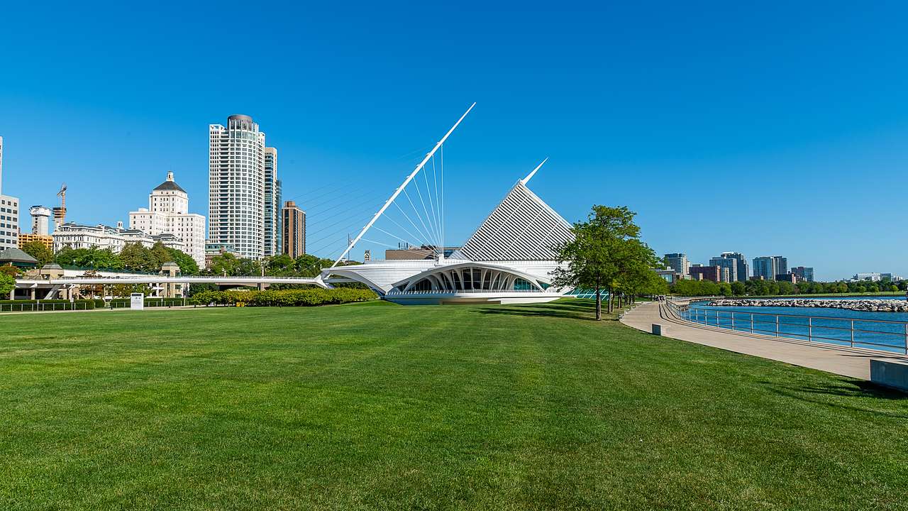 A post-modern structure near a lawn, a body of water, and other buildings