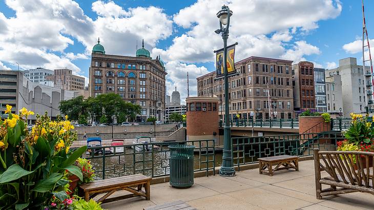 A paved area with benches near a body of water with buildings in the background