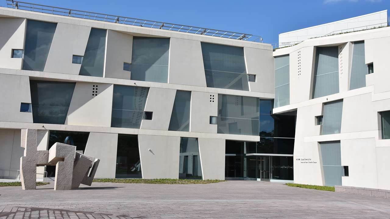A white building with uniquely angled windows and concrete artwork in front