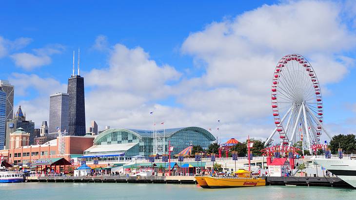 A waterfront with a Ferris wheel and colorful buildings against tall skyscrapers