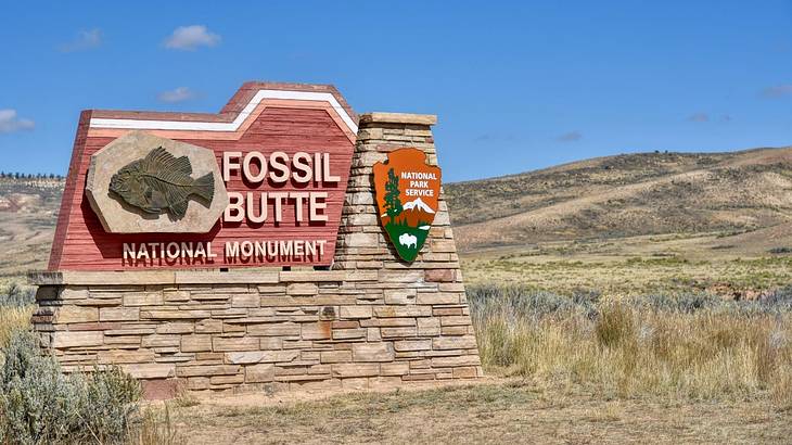 A sign that says "Fossil Butte National Monument" surrounded by hills and grass