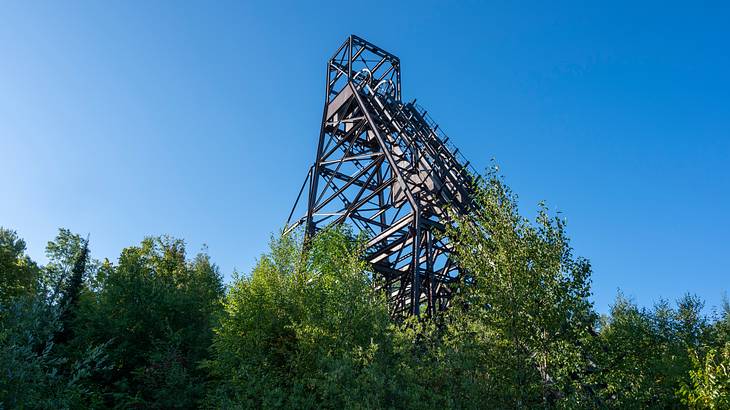 A low-angle shot of old mining equipment with trees in the foreground