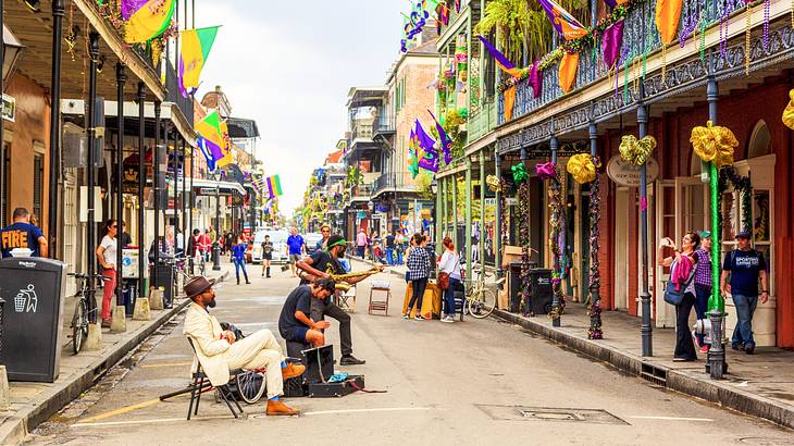 People playing instruments in the middle of a road surrounded by decorated buildings