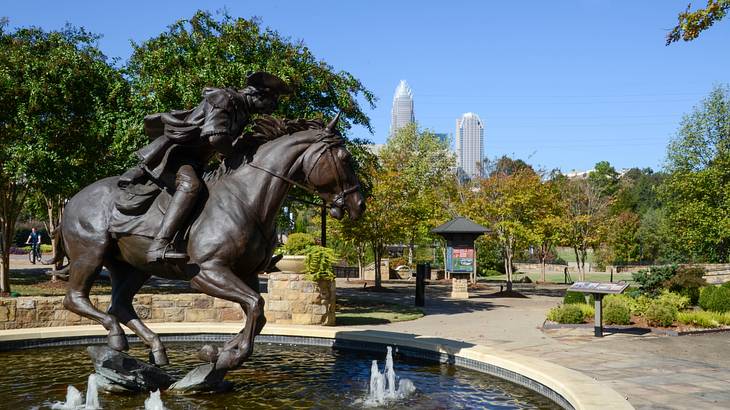 A water fountain with a statue of a man riding a horse near trees