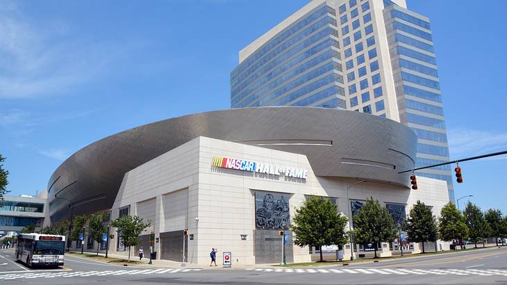 A modern corner building near a road with a sign that says NASCAR Hall of Fame