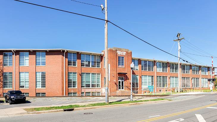 An old brick building near power lines and an empty road