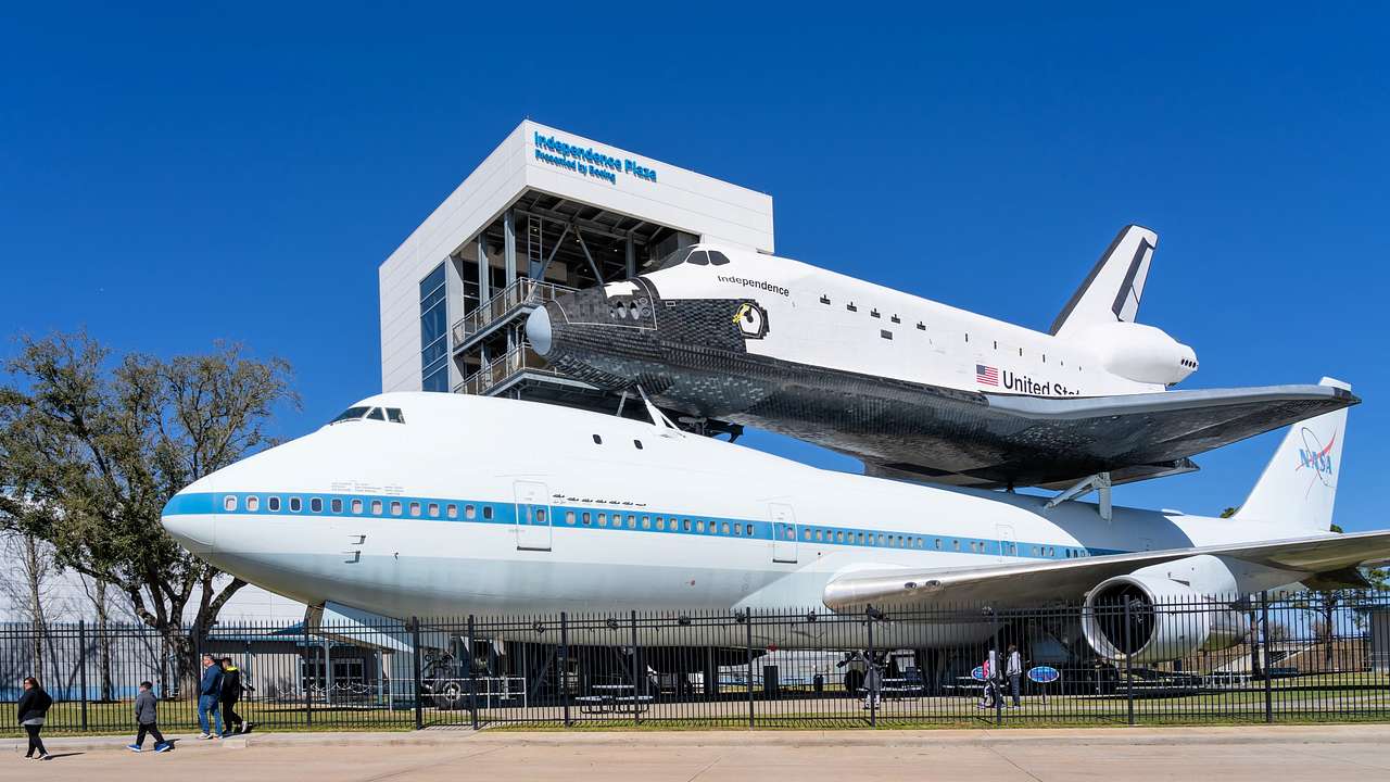 A plane and spaceship model in front of a white building