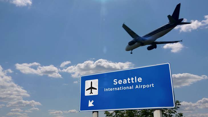 A plane flying over a sign saying "Seattle International Airport"