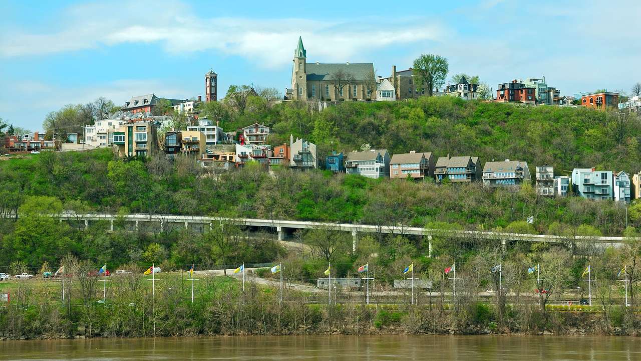Houses built going up a hill with a church at the top next to a river