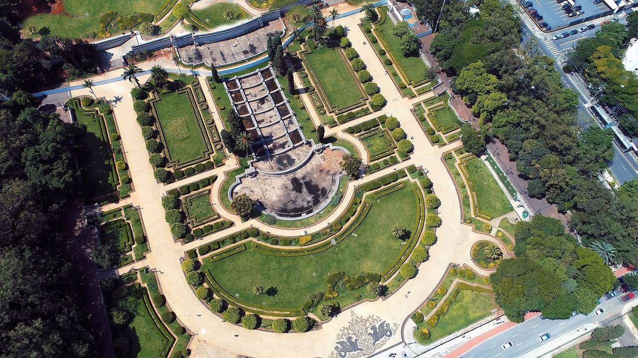 Aerial view of a large park and garden surrounded by city buildings and a road