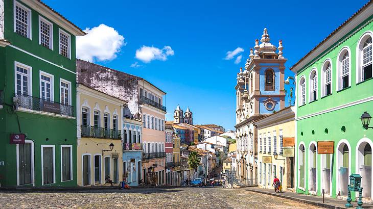 Brightly colored baroque houses along a road under sunny blue skies