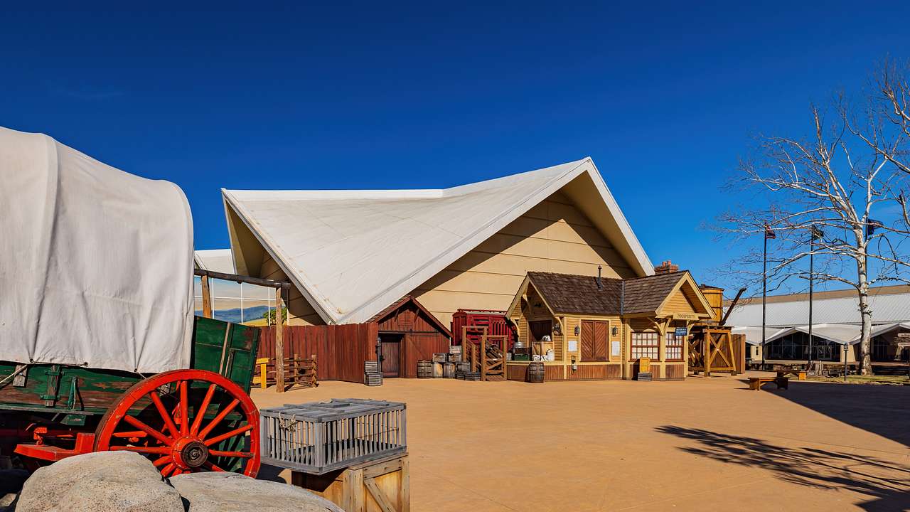 A building surrounded by a covered wagon and other structures