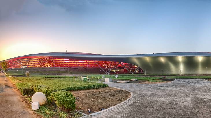 The outside of a big red theme park building with a green lawn and path in front The outside of a big red theme park building with a green lawn and path in front