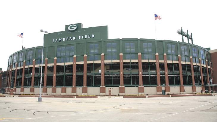 A green football stadium that says "Lambeau Field" with two US flags on it