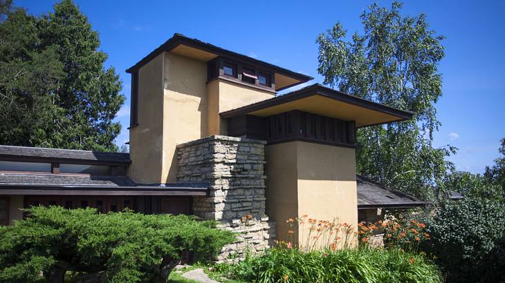 External view of a house with stone accent walls and a flat roof behind a lawn