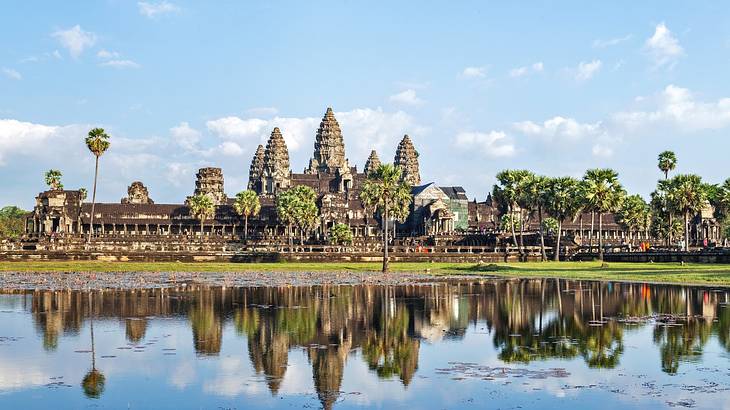 A magnificent, gigantic temple with 5 pointy tops and palm trees reflected in water A magnificent, gigantic temple with 5 pointy tops and palm trees reflected in water