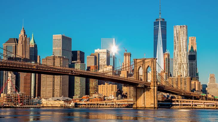 A city skyline with skyscrapers next to a river with a bridge across