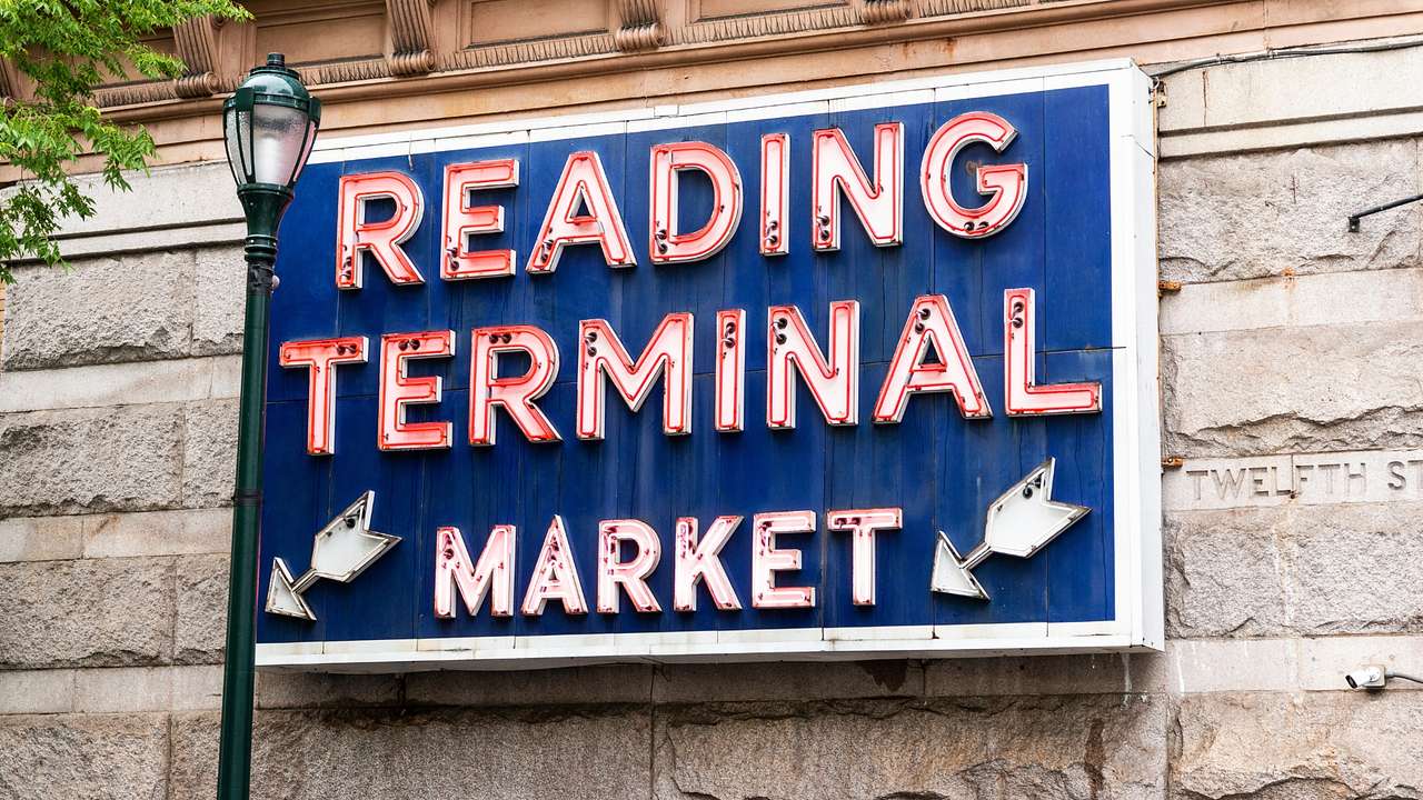 A sign that says "Reading Terminal Market" in red next to a lamppost