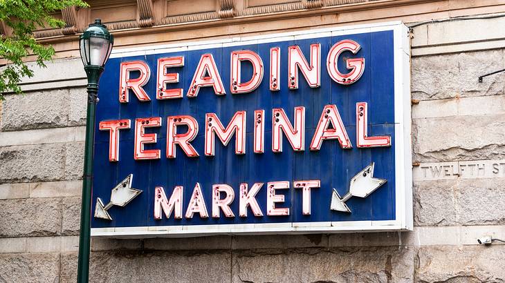 A sign that says "Reading Terminal Market" in red next to a lamppost