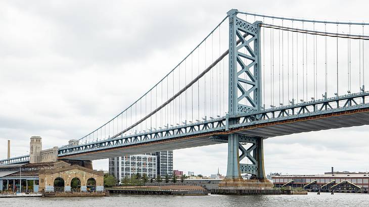 A bridge over a river with a stone building on one side under a cloudy sky