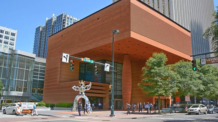 A modern square-shaped building with a contemporary silver statue in front of it