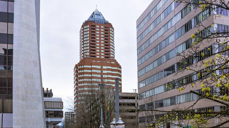 A tall orange-brick tower with many windows next to other buildings