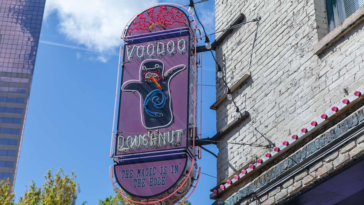 A pink and purple neon sign saying "Voodoo Doughnut"