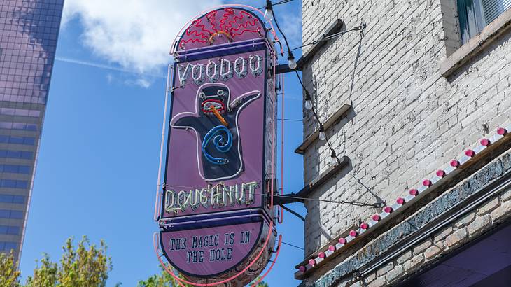 A pink and purple neon sign saying "Voodoo Doughnut"