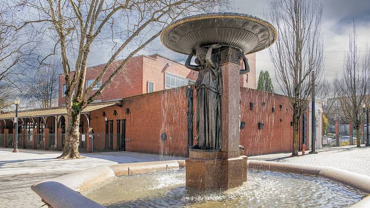 A statue fountain with a sculpture of a woman carrying a basin-like structure