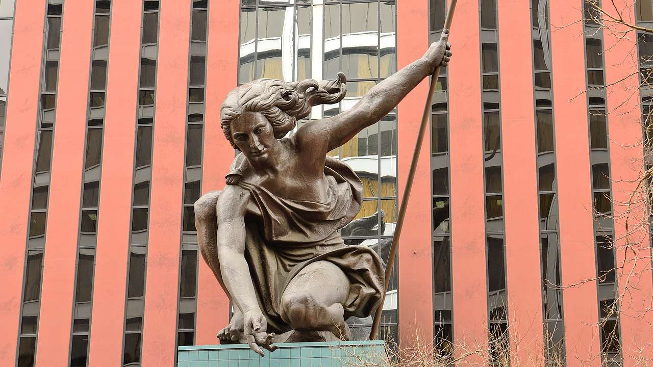 A copper statue of a woman holding a trident