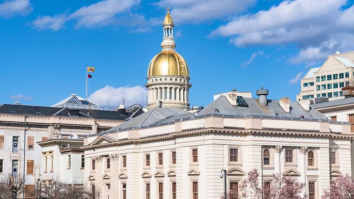 An old white building with gray roofs and a gold dome top