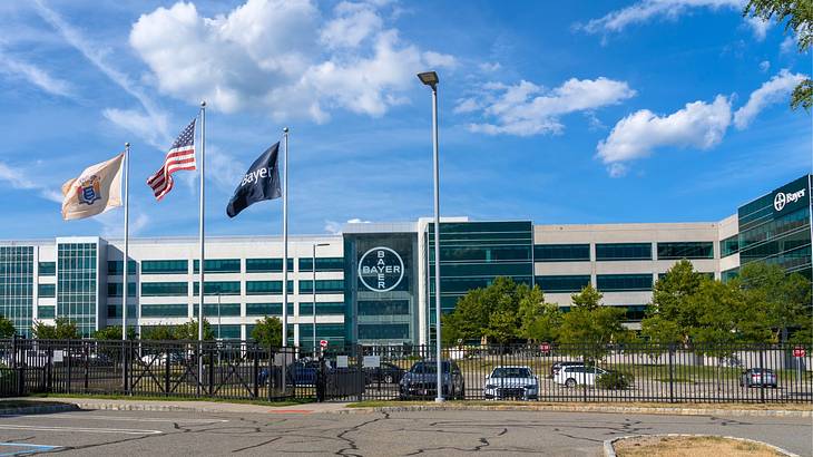 A gated building complex with a parking lot and flagpoles in front