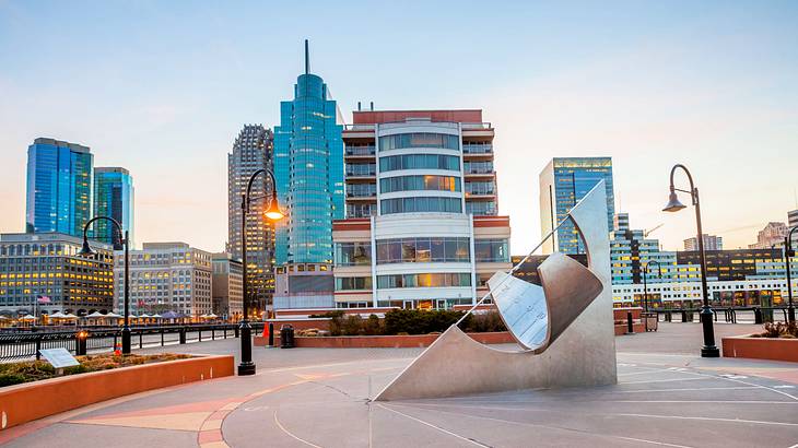 An art installation near a lit lamppost in an urban park near buildings during dusk