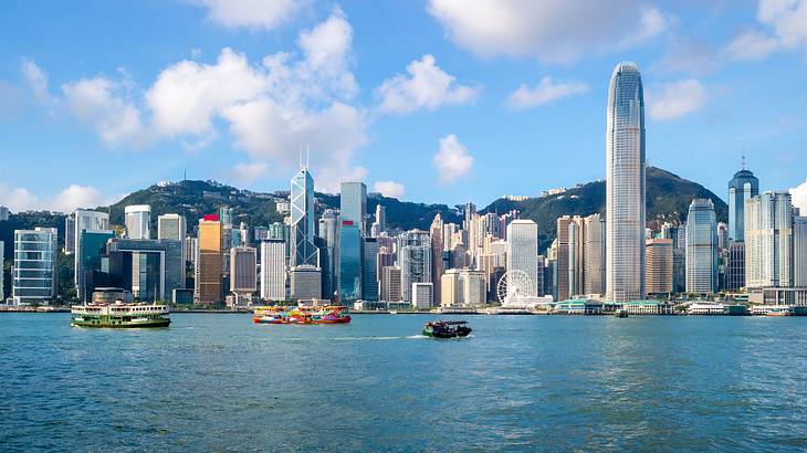 A city skyline with a hill behind and a harbor with boats in front