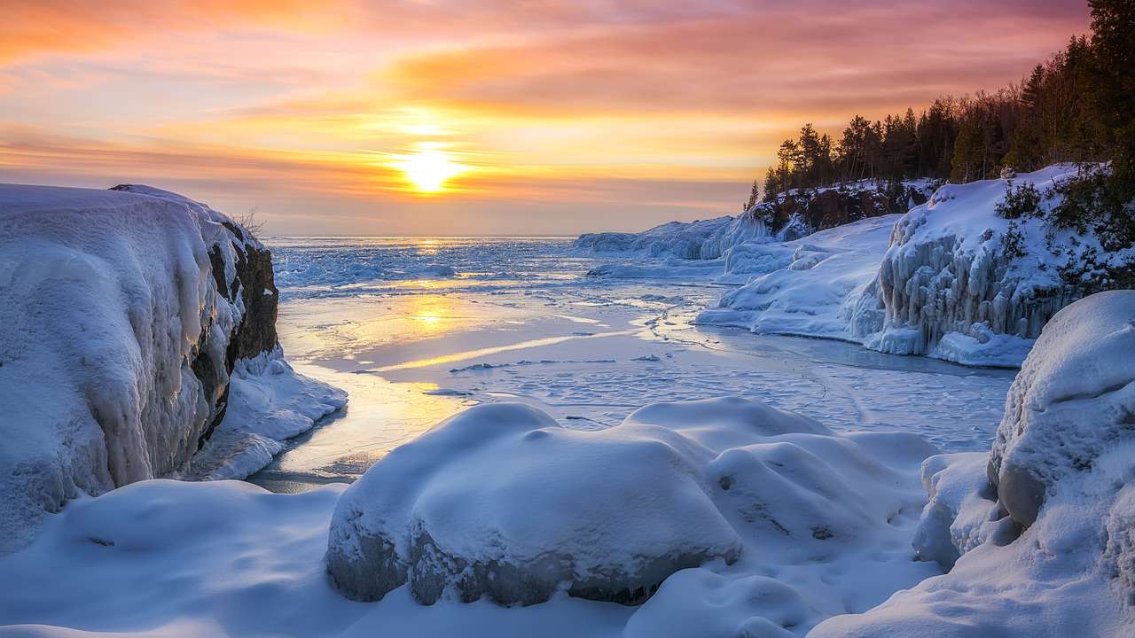 A shore covered heavily with snow during sunset