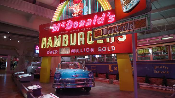 A neon LED signage of "McDonald's" with a vintage car below it