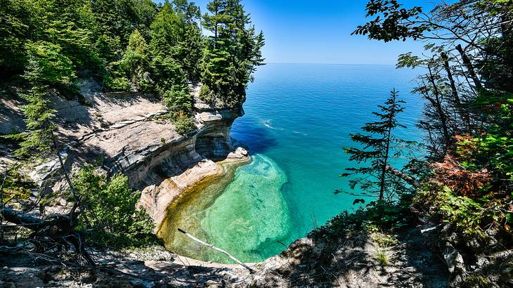 A forested rock formation near clear waters