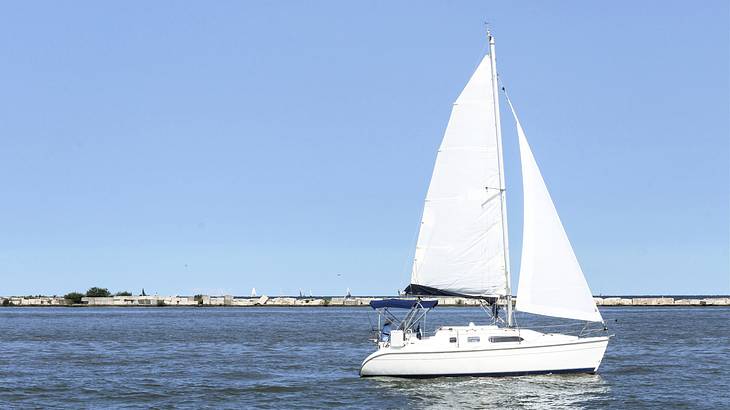 A white sailboat on a body of water under a clear blue sky
