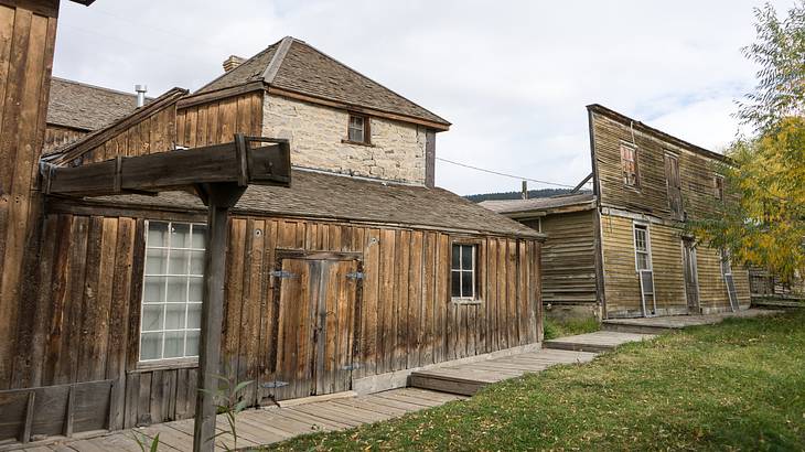 A grassy lawn in front of rustic wooden structures against a cloudy sky