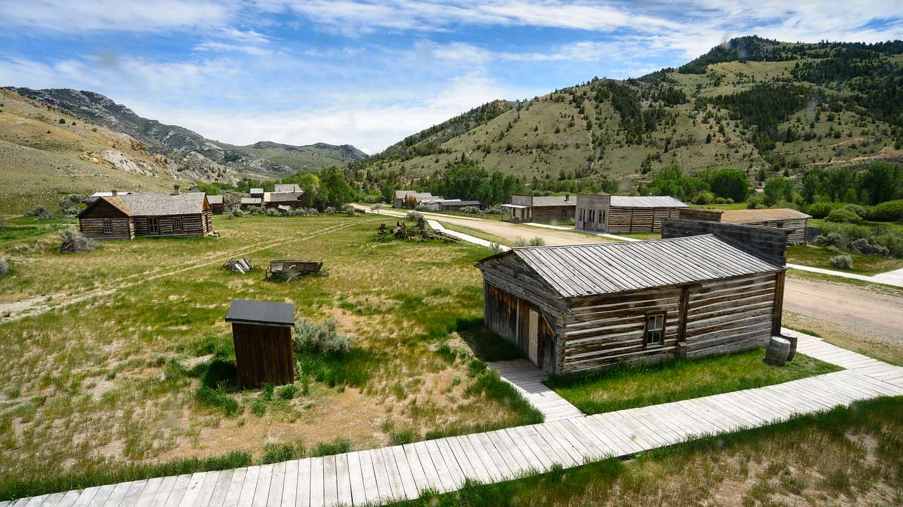 A path walk connecting wooden houses on a valley with mountains in the background