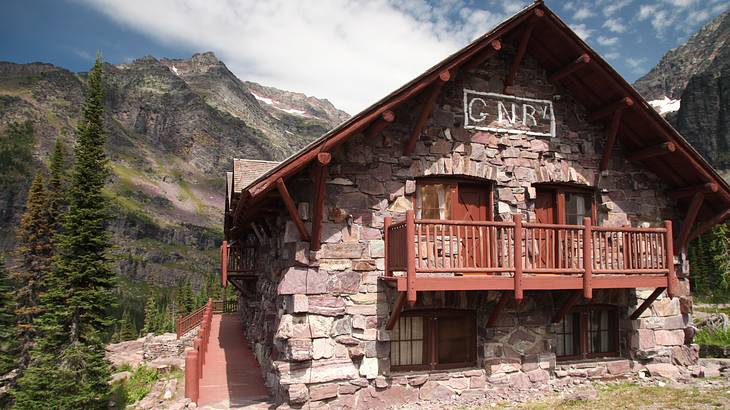 A house made of bricks and wood surrounded by pine trees with a view of a mountain