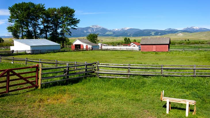 Snow-capped mountains in the background of a ranch with barn, houses and wooden fence