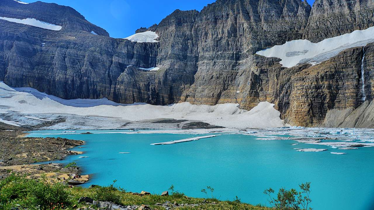 Glaciers on a rocky mountain with a turquoise-colored river at its foot