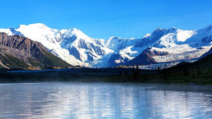 Snow-capped mountains overlooking blue water under a clear sky