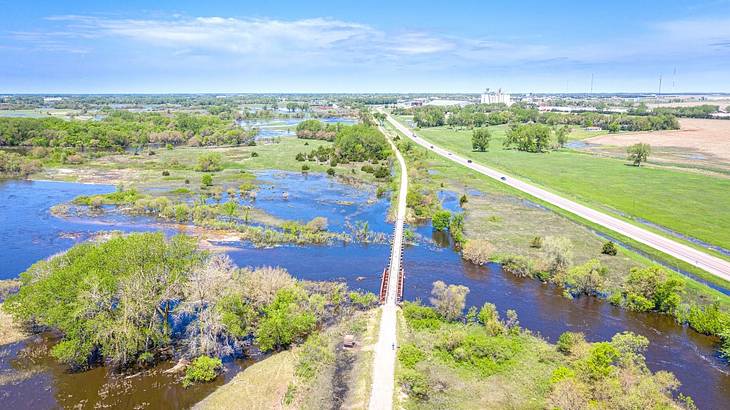 An aerial of a trail and a road going through a river and grassland