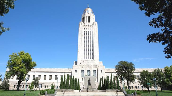 A white stone building with a tower and trees and steps in front of it