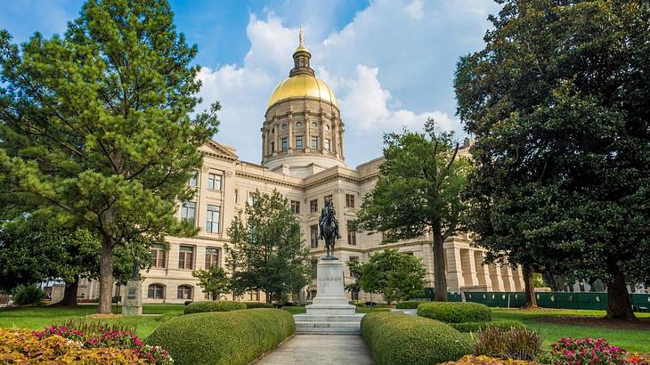 A regal building with a gold-domed roof and a garden in front of it