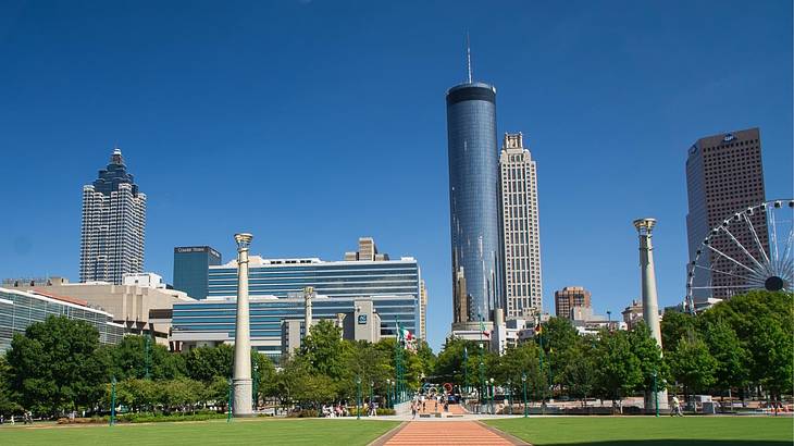 Skyscrapers and a Ferris wheel with a path and green grass in front