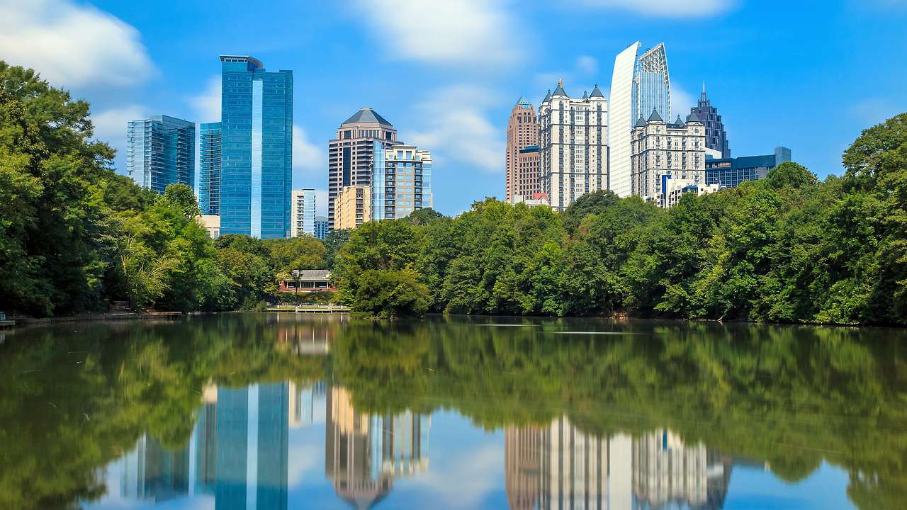 A lake with a reflection in the water of the trees surrounding and a skyline it